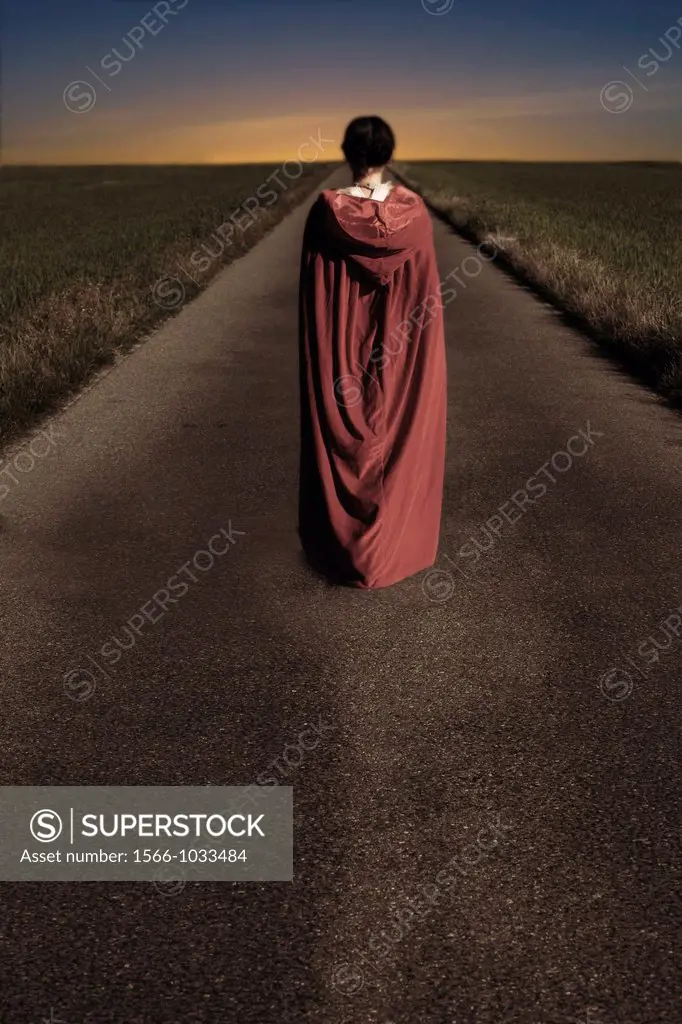 a woman in a red cape is walking along a road