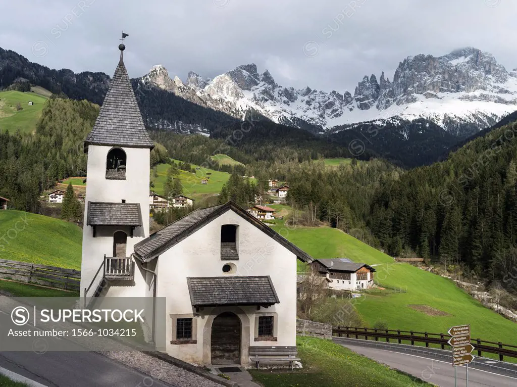 Rosengarten or Catinaccio mountain range in the dolomites of South Tyrol after a snow storm in spring The little church of Saint Zyprian and Justina i...