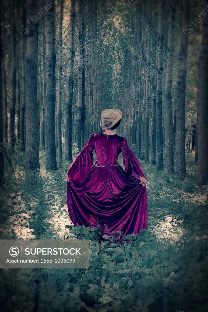 a woman with a period dress standing in a forest