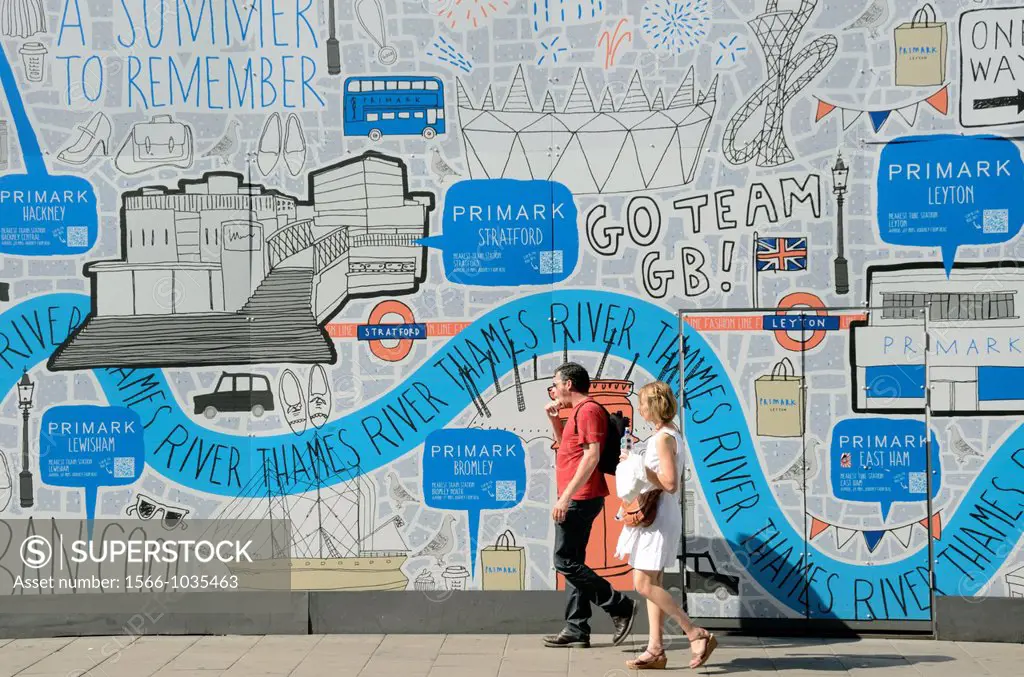 Couple walking past hoarding advertising Primark stores, Oxford Street, London, UK