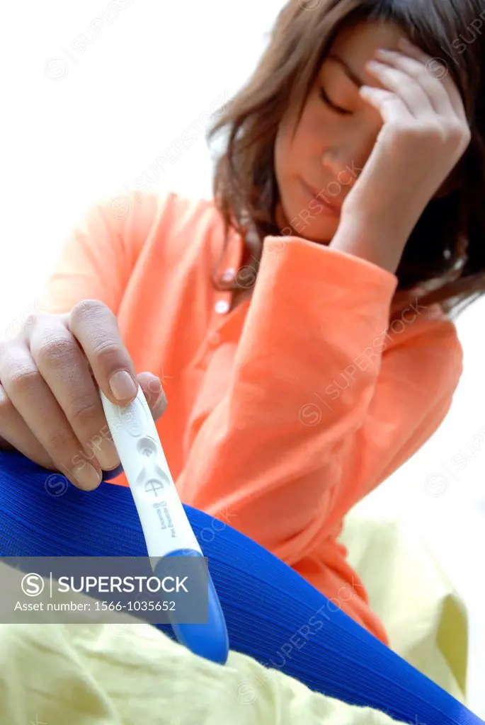 Home pregnancy testing  Stressed young woman holding a home pregnancy test kit showing a positive result