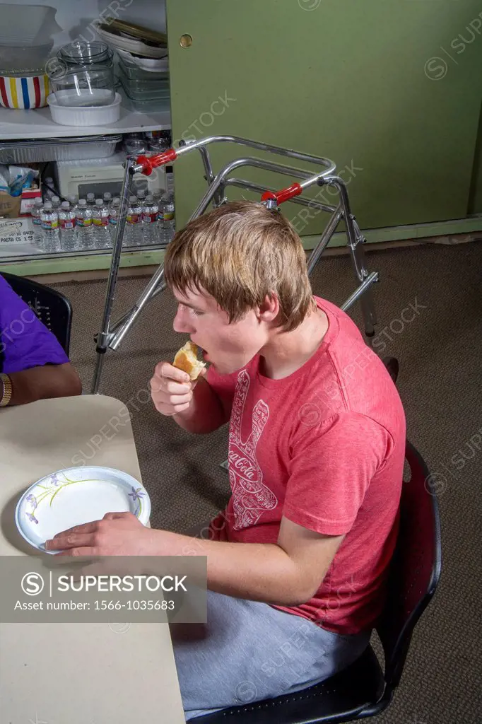 A blind and handicapped teen boy samples food from a baking and cooking class at the Blind Children´s Learning Center in Santa Ana, CA  Note walker
