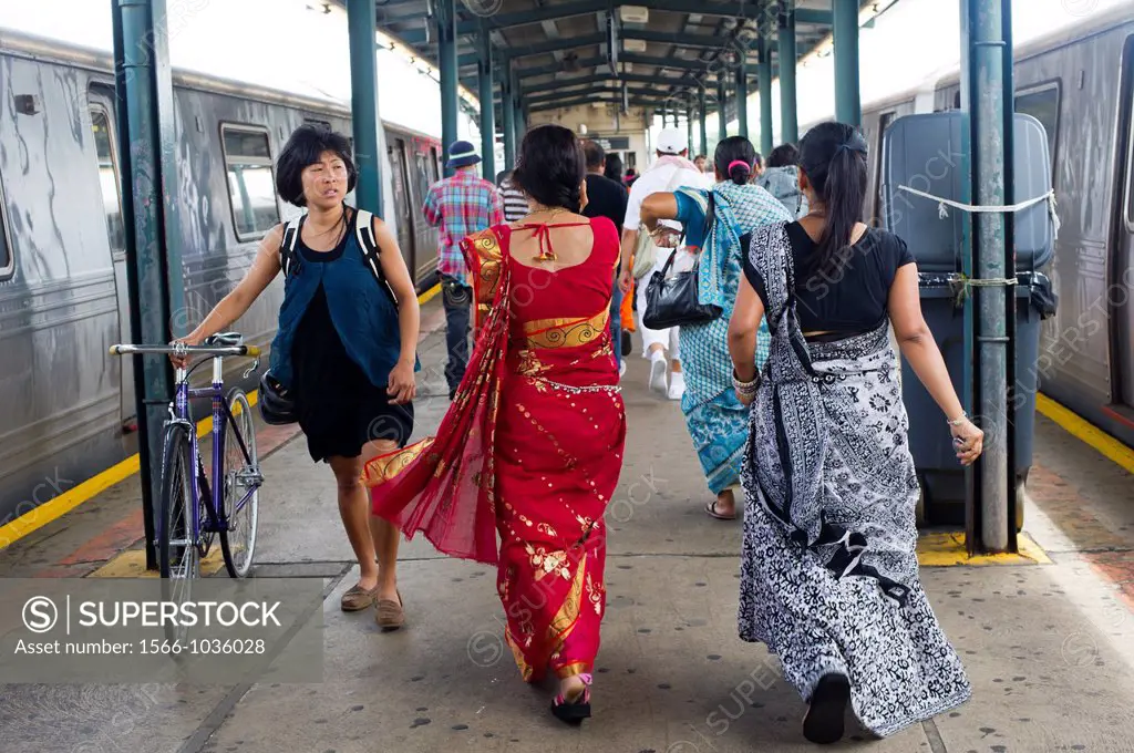 Women dressed in saris pass an Asian woman walking her bicycle at the subway in Richmond Hill in the New York borough of Queens The neighborhood of Ri...