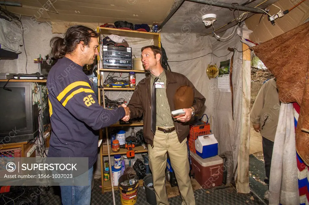 A local minister visits an indigent military veteran in a makeshift shelter among homeless residents of a primitive outdoor encampment in the desert t...