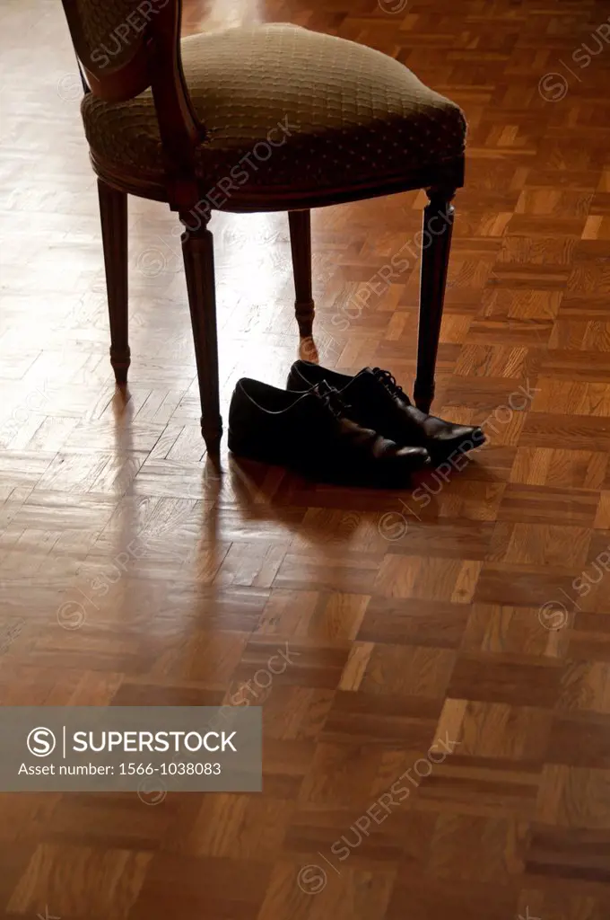 men´s black shoes next to old fashioned chair, on the wooden floor, home, after work private life