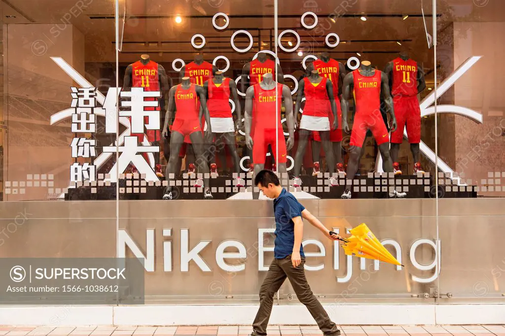 Shopper walks past the Nike shop along Wangfujing Street shopping district on a rainy day in Beijing, China
