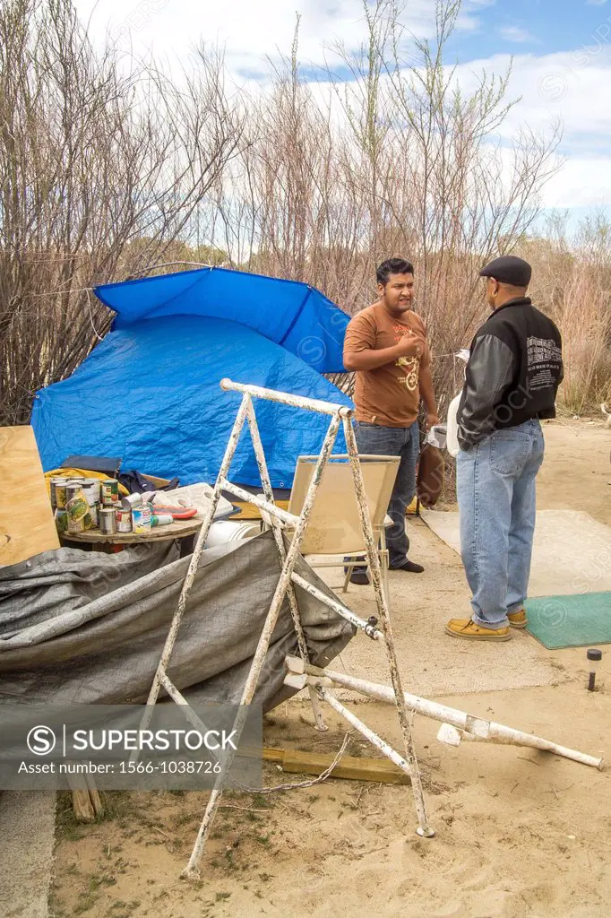 An African American charitable church representative talks with a homeless man living in an outdoor encampment in the desert town of Victorville, CA