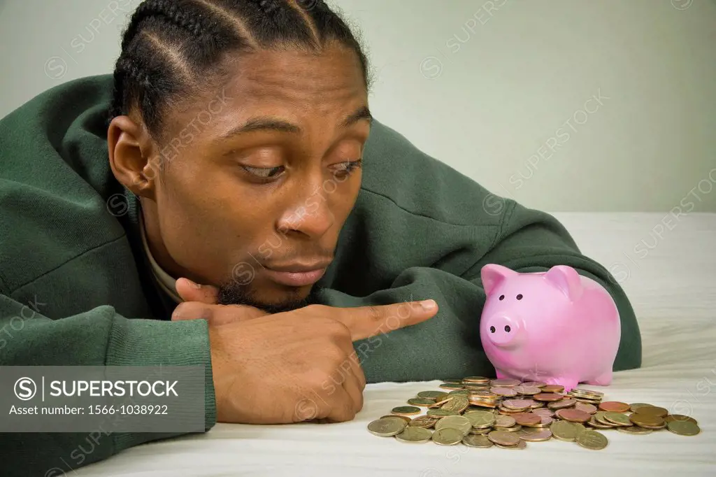 Young black man with United States coins and a piggy bank