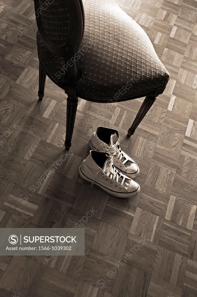 pair of sneakers on the wooden floor next to the old time chair, Sepia image, monochromatic image