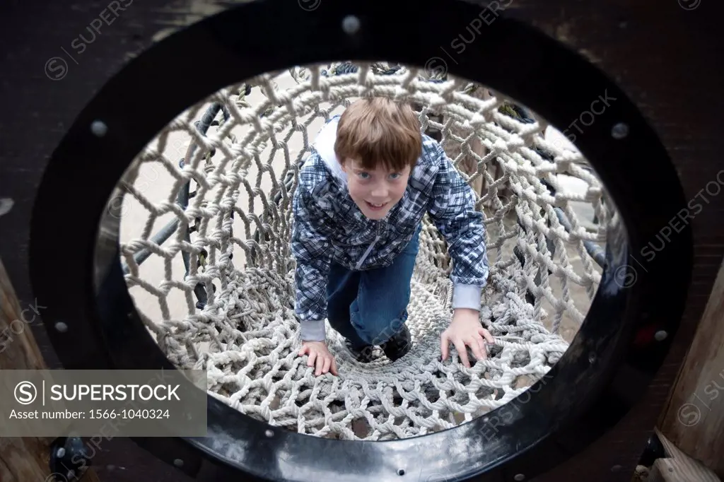 boy triumphantly climbing rope tunnel