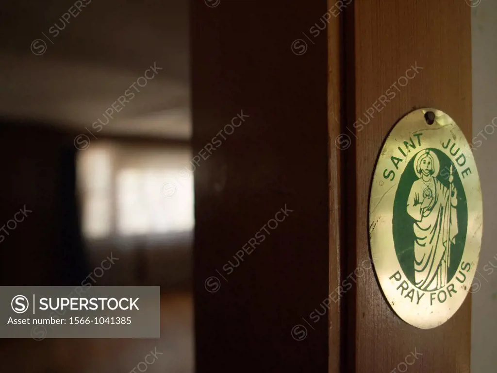 A Saint Jude medal hangs on the inside of a foreclosed house in Milbury, Masachussetts, United States