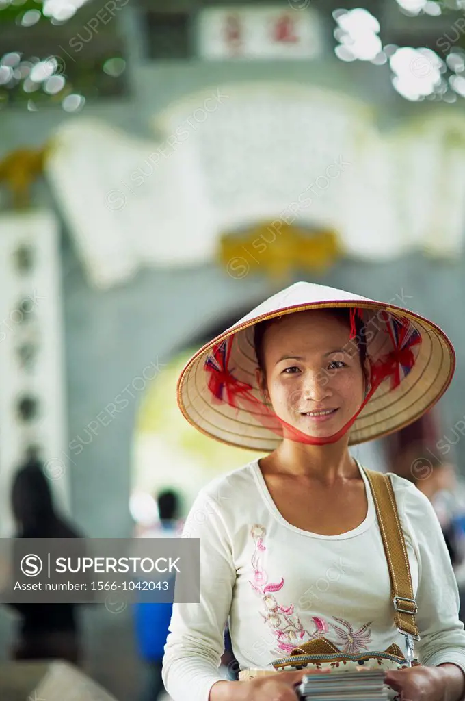 A portrait of a Vietnamese woman wearing a nón lá or a traditional Vietnamese straw hat contrasted with modern clothes