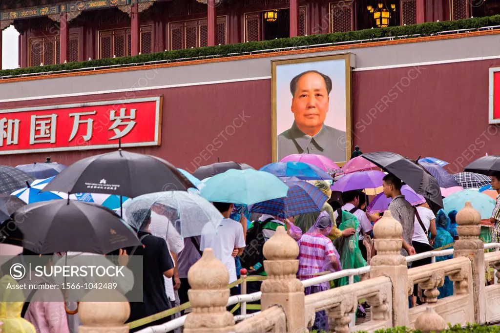 Tourists sheltering under umbrellas stream into the Forbidden City during a rainy summer day in Beijing, China