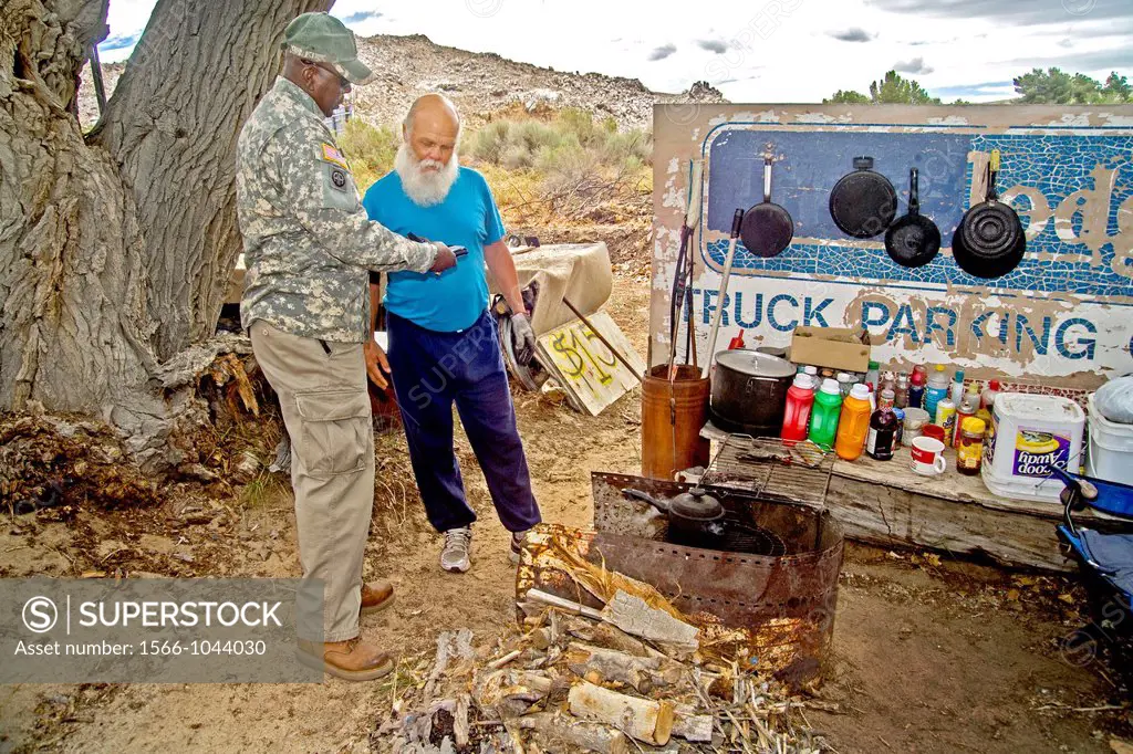 A uniformed African-American U S  Army reservist offers a homeless military veteran information on Veterans Administration free medical care at an out...