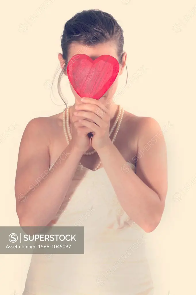 a woman in a wedding dress holding a heart in front of the face