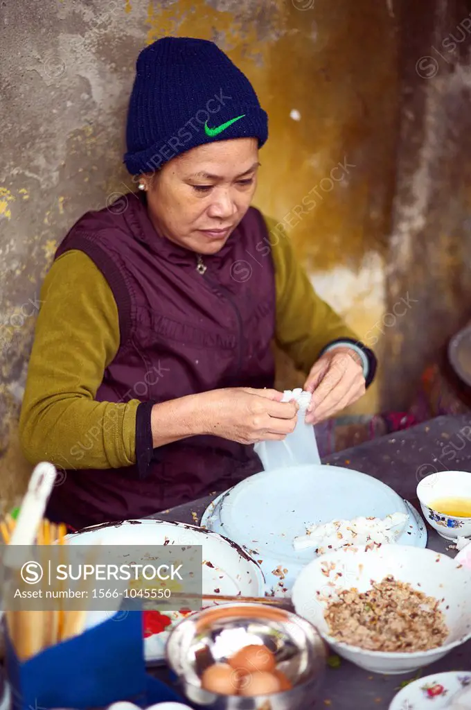 A woman making banh cuon, or rolled stuffed rice noodle, on the streets of Vietnam