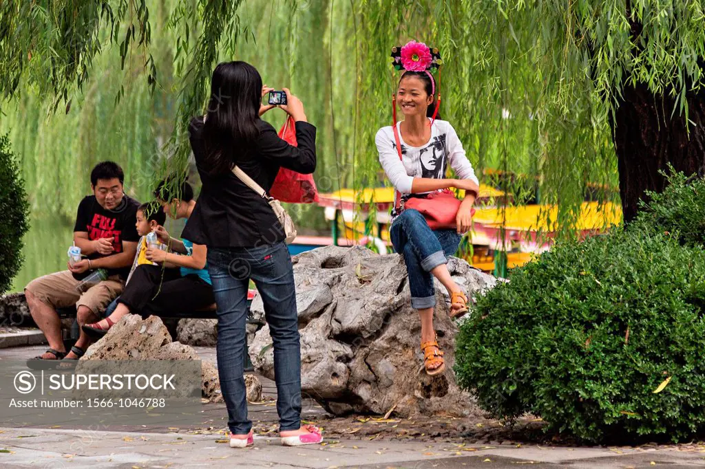 A woman has her picture taken wearing a traditional headdress at Beihai Park in Beijing, China