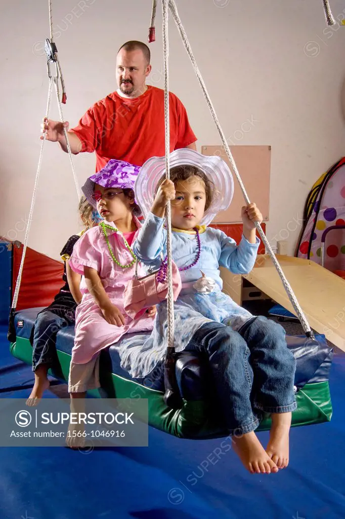 As a teacher watches, partially blind girls wear costumes for dress-up as they ride a swing during an occupational skills class at the Blind Children´...