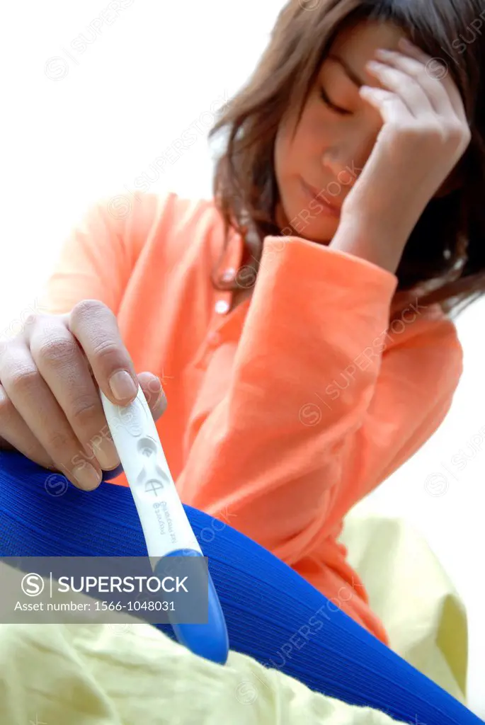 Home pregnancy testing  Stressed young woman holding a home pregnancy test kit showing a positive result