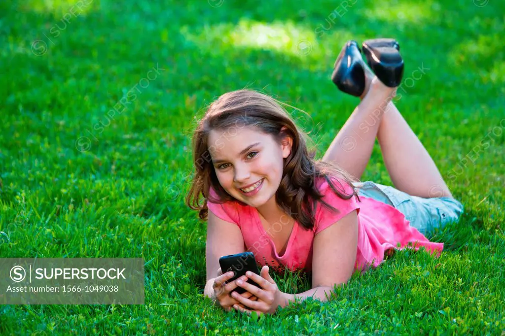 young girl lying on lawn listening to music