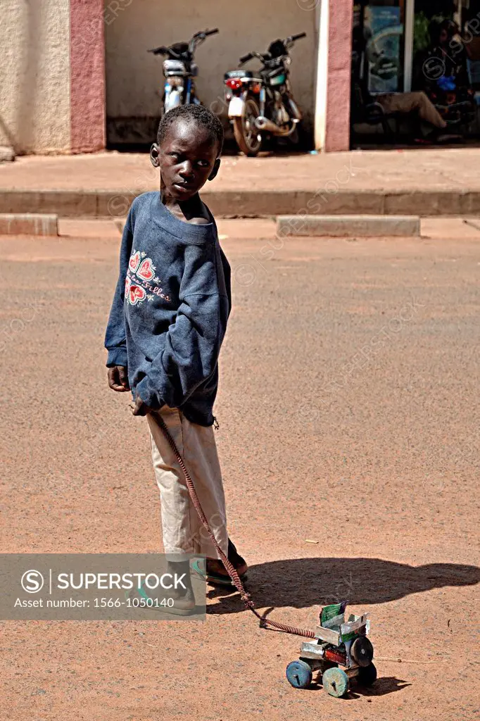 A child drags his toy car made from recycled materials, Segou, Mali