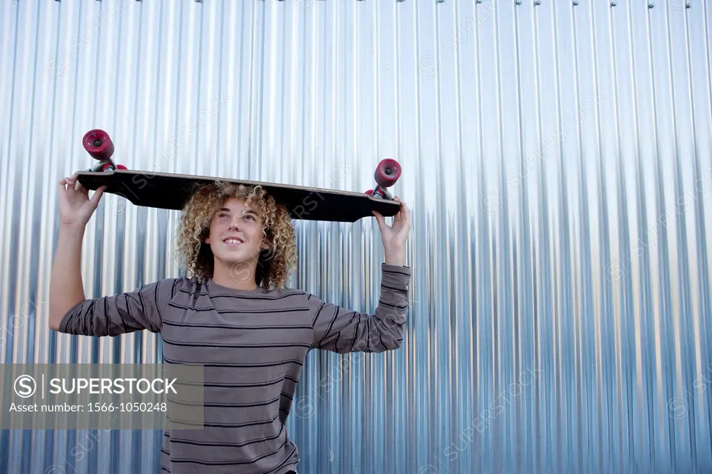 Teenage boy holding a longboard on his head
