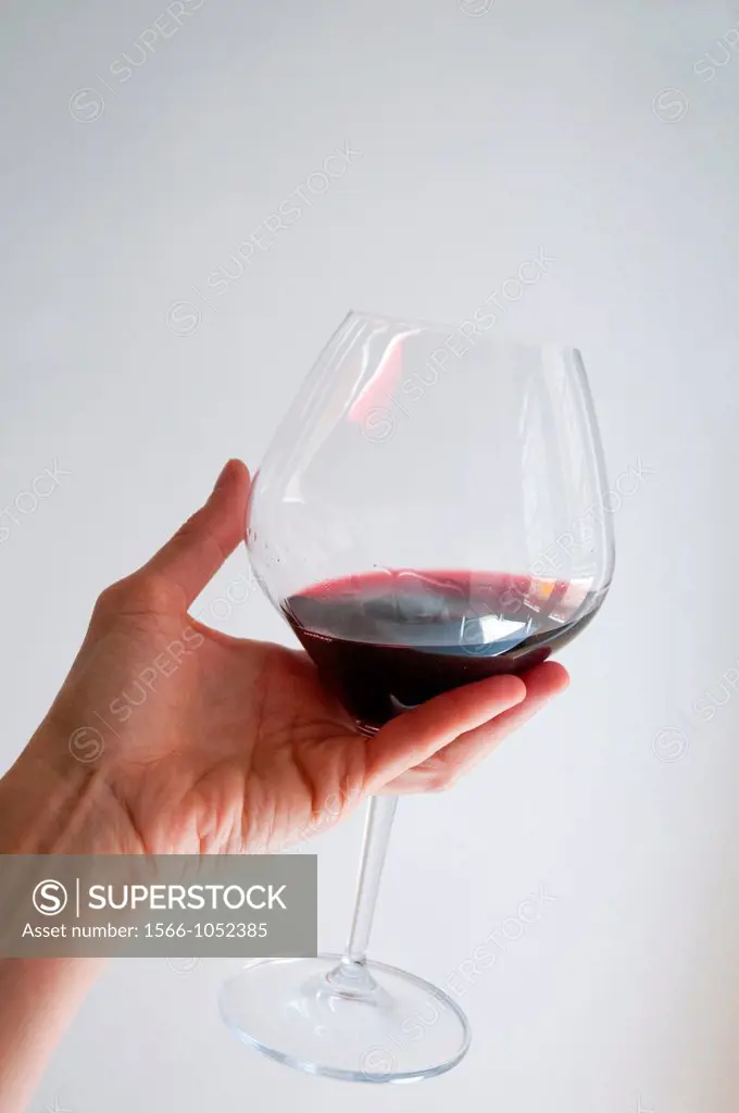 Woman´s hand holding a glass of red wine, tasting it