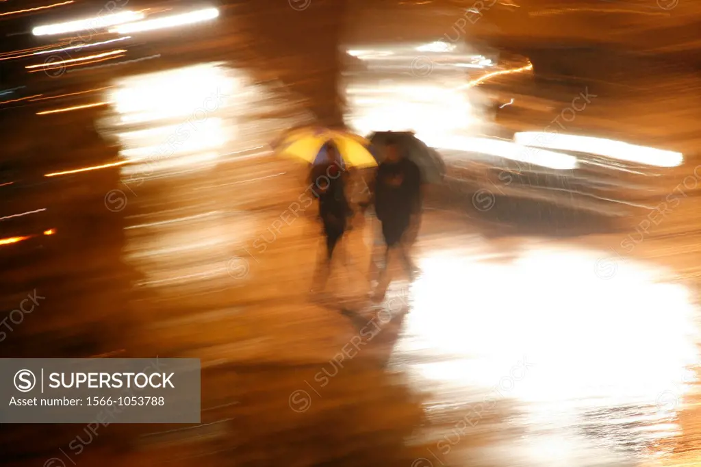 person with umbrella heavy rain at night in town