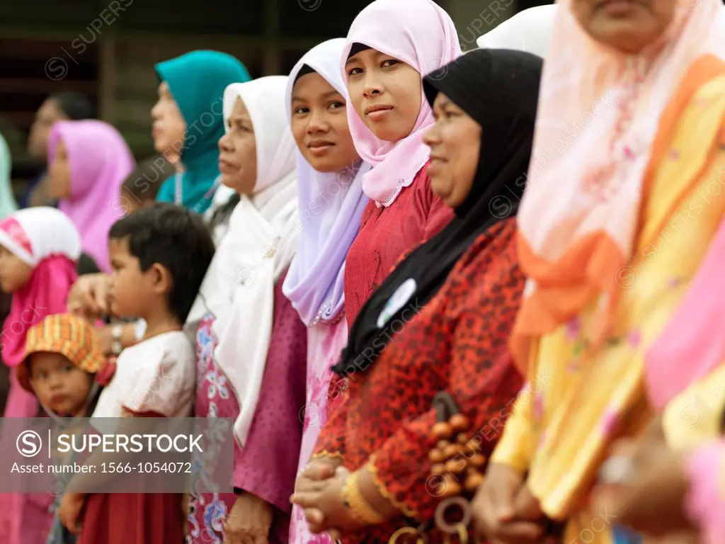 Traditionally dressed women and children standing and smiling during a rally in Malaysia