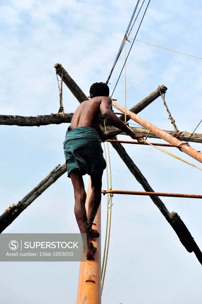 Indian man working with chinese fishing nets in Kochi,Kerala,South India,India,Asia