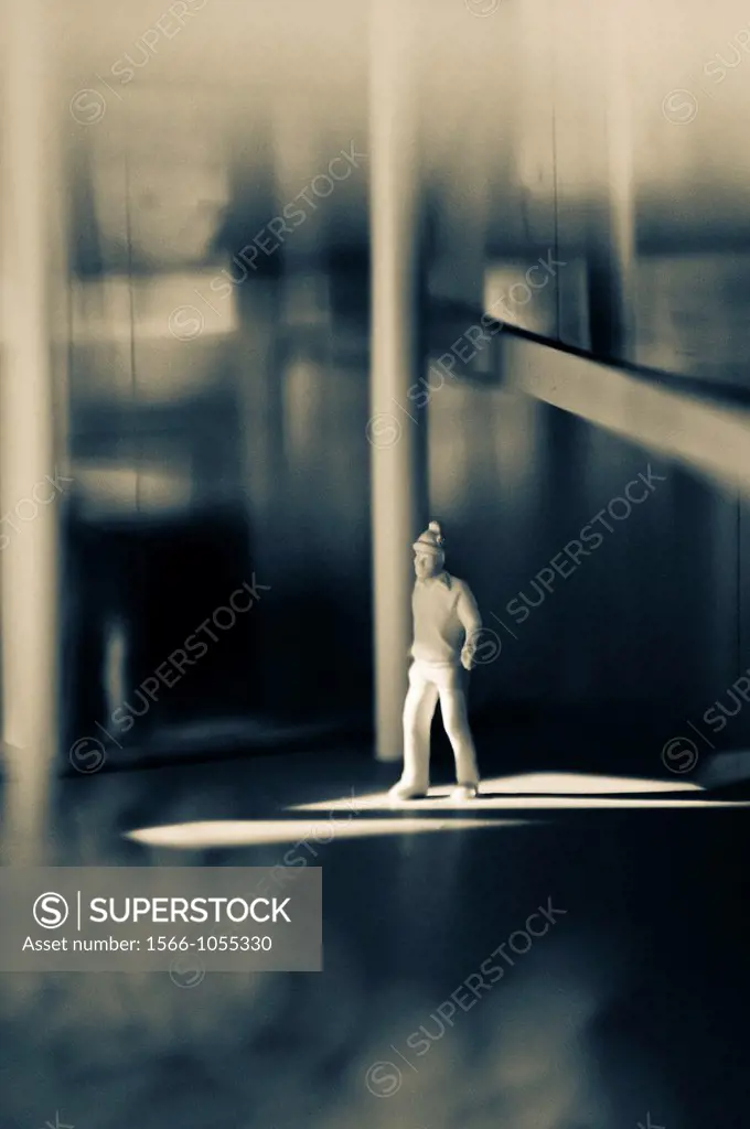 Miniature model of a man with wooly hat crossing a shaft of light