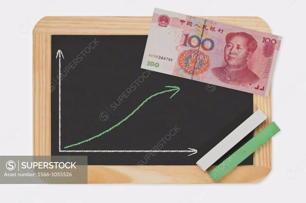 Detail photo of a chalkboard. A chart with an increasing curve on this. On the chalkboard lies a Chinese 100 Yuan banknote with the portrait of Mao Ze...
