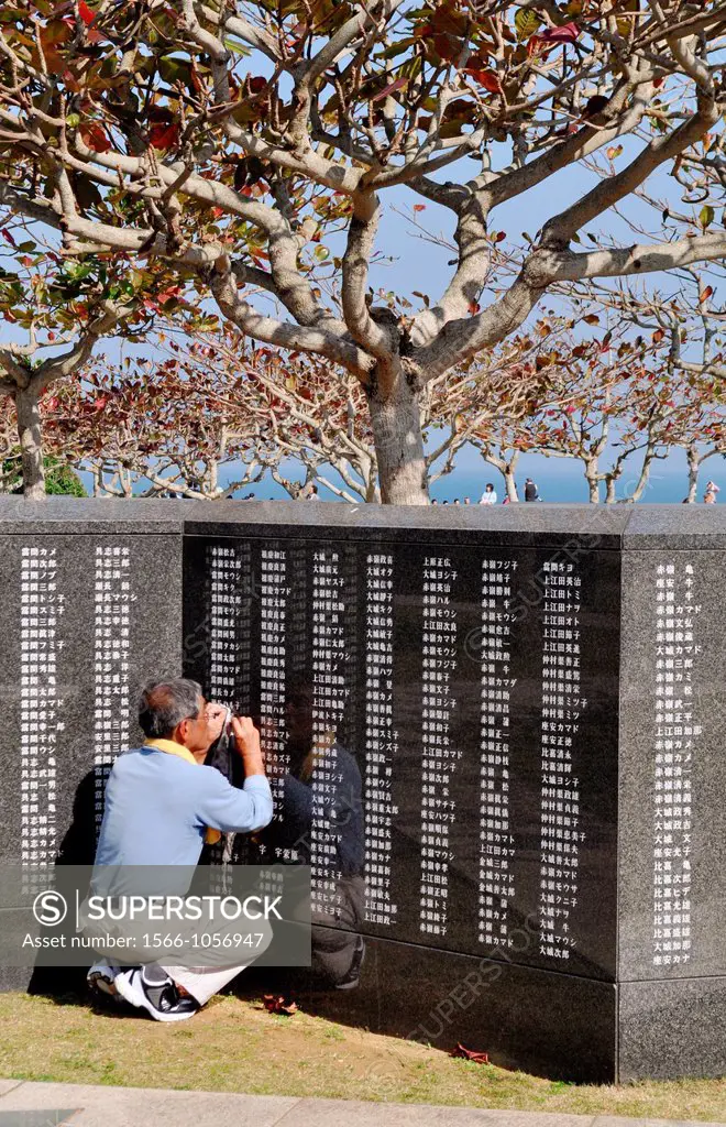 Okinawa, Japan: a man refreshing the paint of the victims names at the Peace Memorial, to remember the many Japanese people that committed suicide dur...