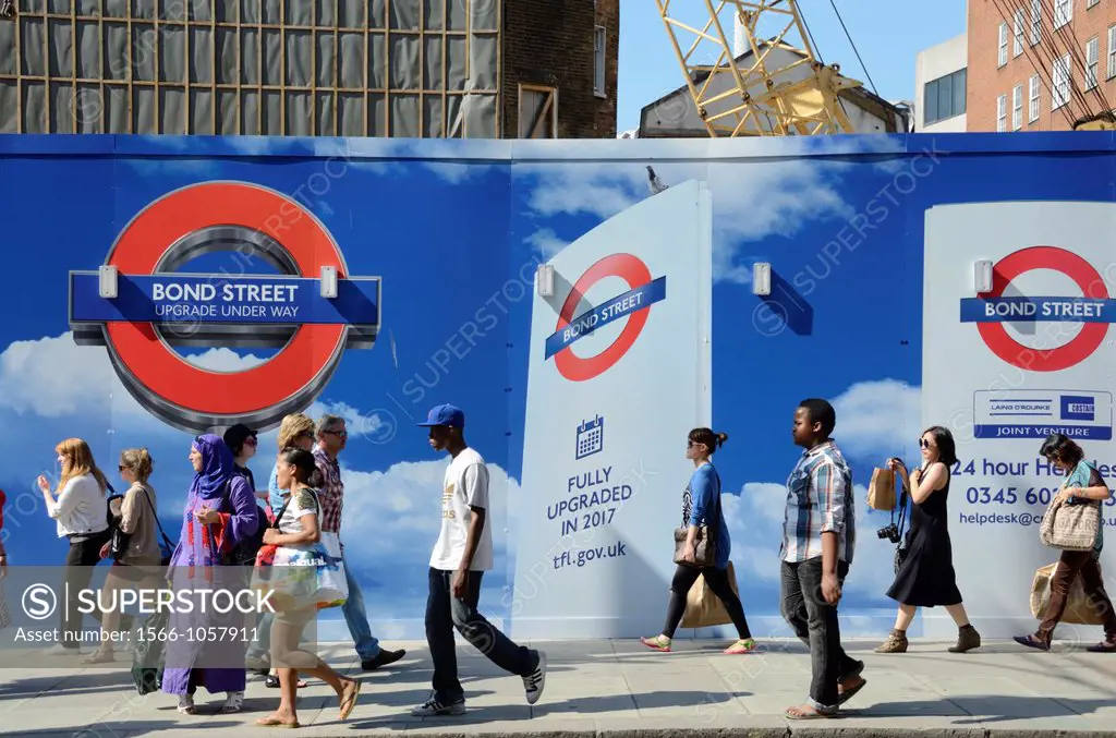 Shoppers walking past Bond Street Underground Station upgrade hoarding, Oxford Street, London, UK  The upgrade is due to be completed in 2017