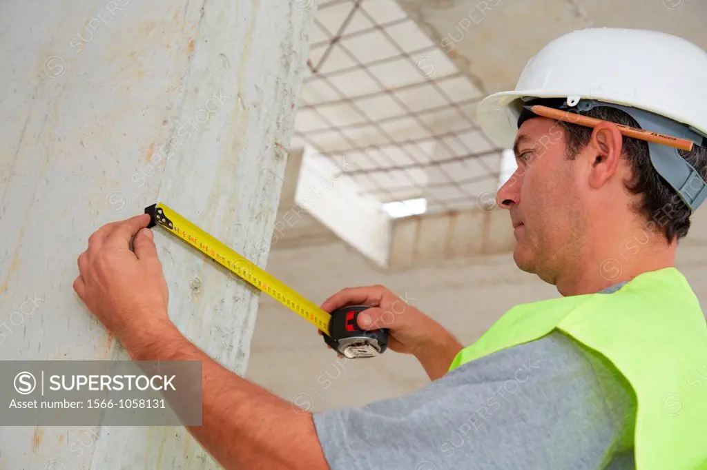 Worker with protective equipment, PPE, Taking measures in concrete beam, retractable tape, housing construction, Basque Country, Spain