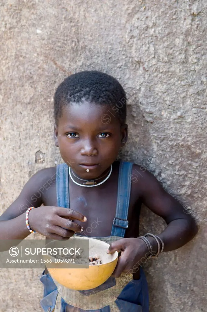 A cute little girl eating lunch by her home in a small village in Northern Benin near the Togolese border