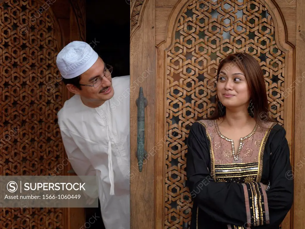 Arab Muslim Malaysian father and daughter looking at each other in front of an intricately designed doorway