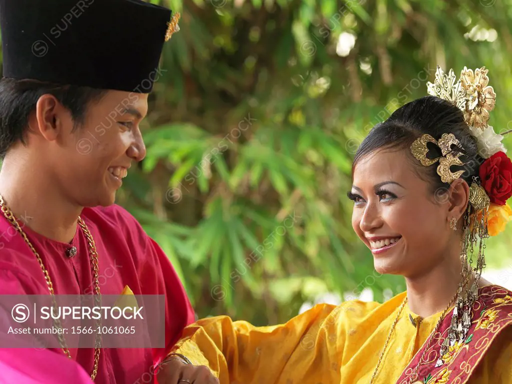 A couple dressed in traditional costume smiling at each other