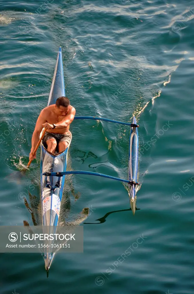 Man paddles outrigger canoe