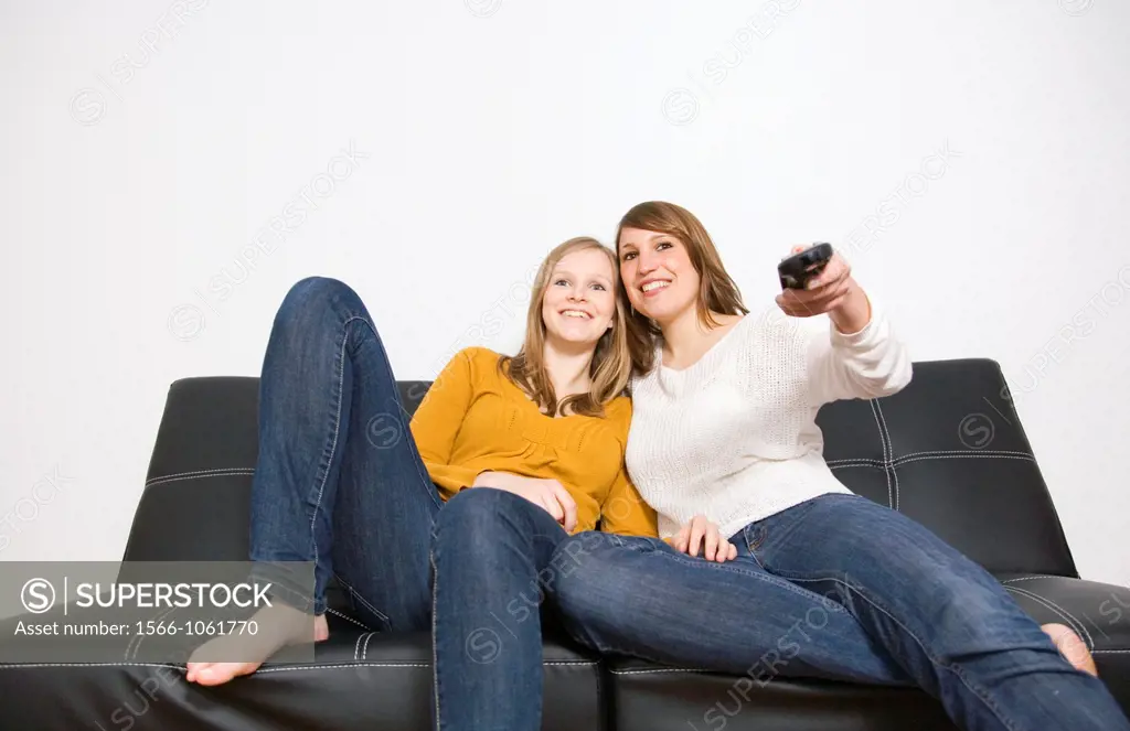 Two beautiful young women watching TV on the couch