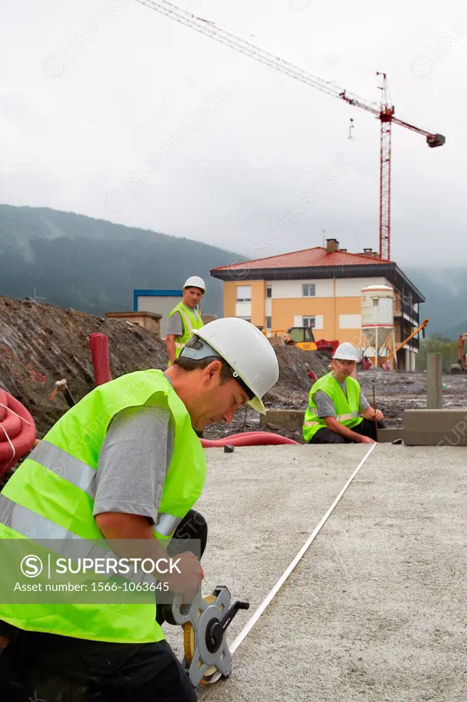 Workers with protective equipment, PPE, Taking measures in urbanization, Outside, Housing construction, Measuring tape, Basque Country, Spain