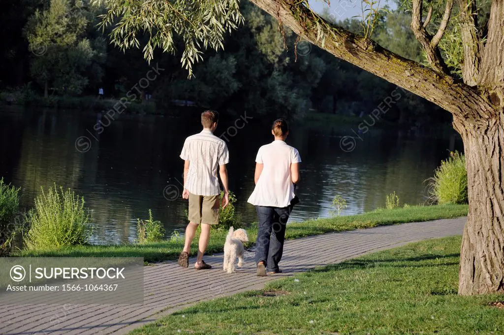 A couple and a dog stroll along the Avon River in Stratford, Ontario, Canada where a famous Shakespeare festival is held every year