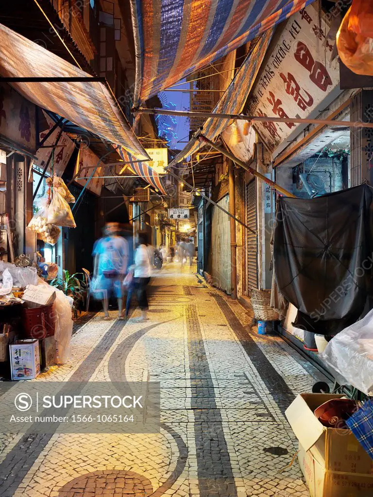 The street of Leal Senado de Macau is illuminated by lampposts and storefronts in the early evening as Macanese and Tourists alike travel back and for...
