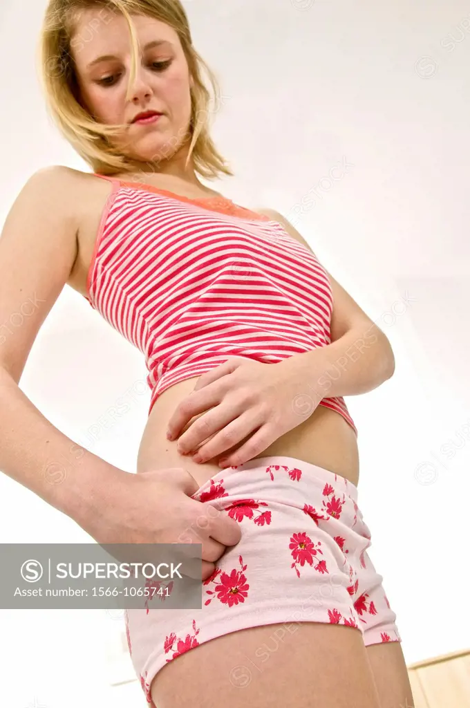 arms of young woman scratching her itching hip in red underwear, suffering  from psoriasis or a rash - SuperStock