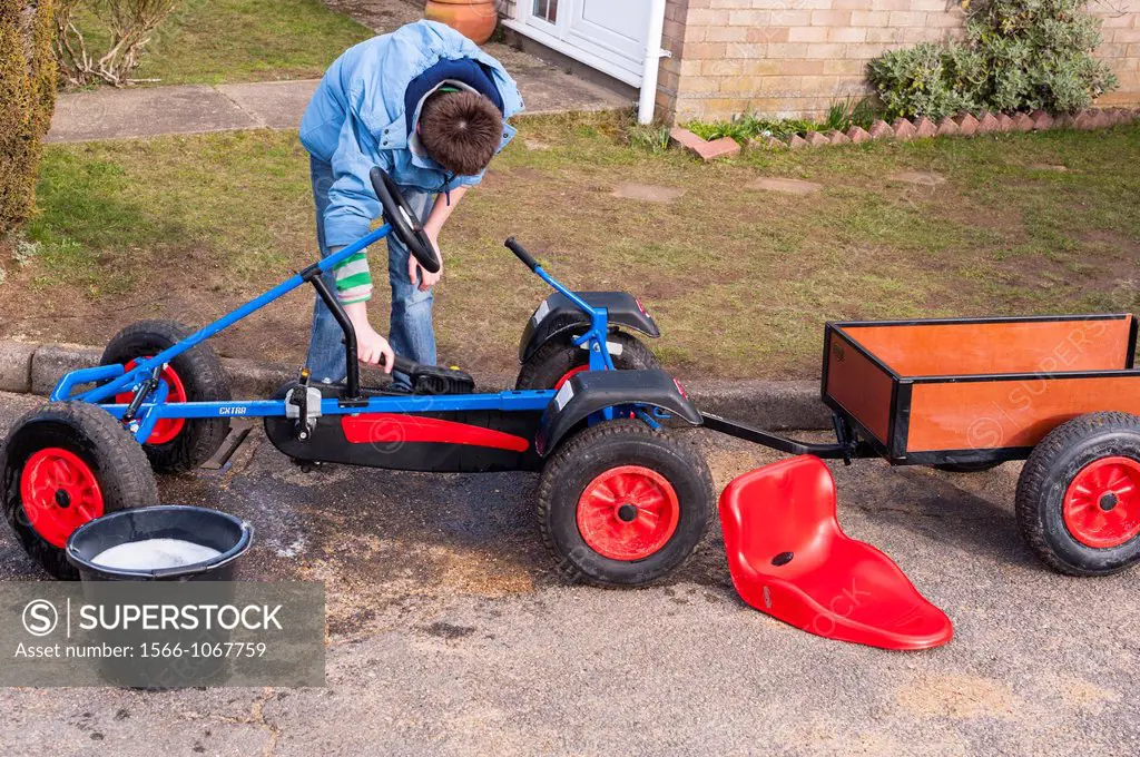 A 12 year old boy washing and cleaning his gocart in the Uk
