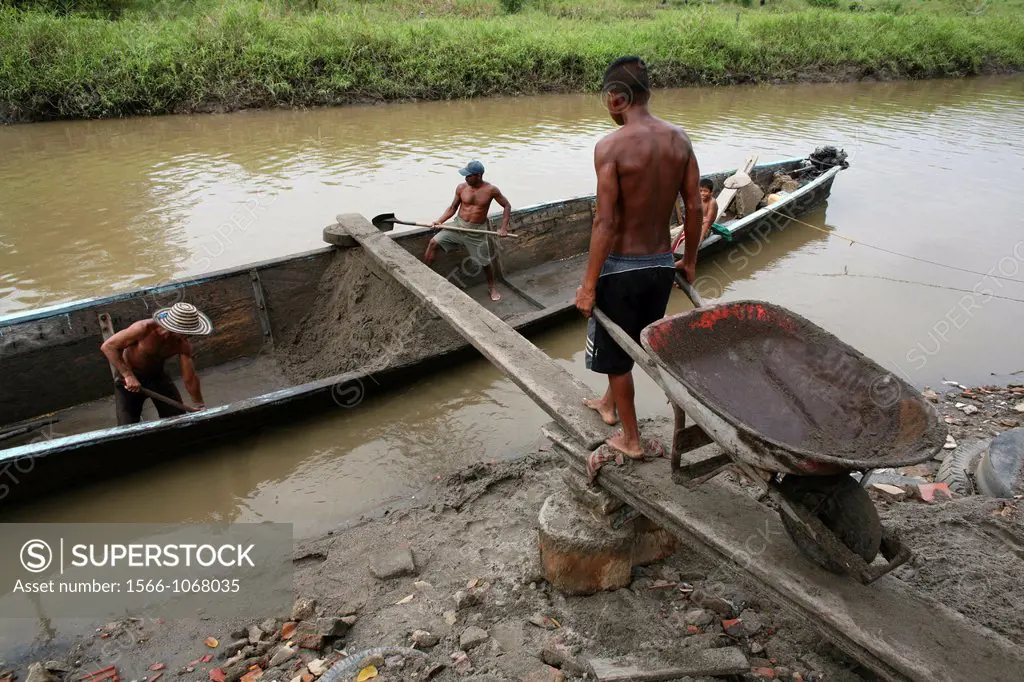 Poor people dig sand from the bottom of the river and transport it with canoes to the shoreline and sell it to businessmen