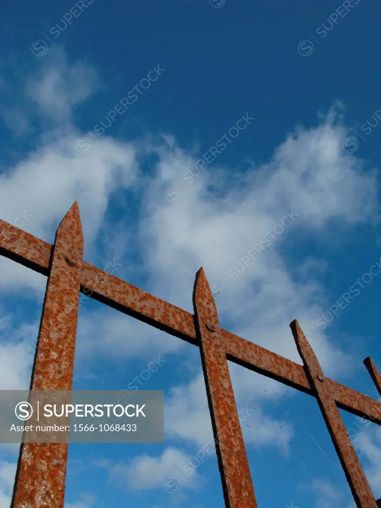 old rusty brown wrought iron gate and blue sky