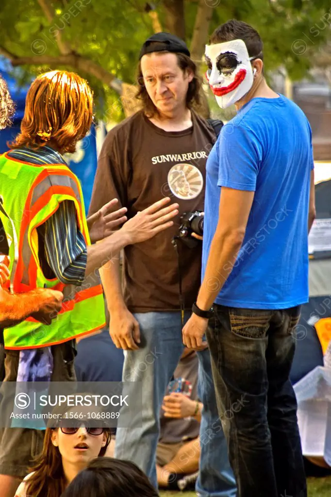 A clown-face masked protester joins others in expressing the We-Are-the-99 anti-capitalism sentiments of Occupy Wall Street at Los Angeles City Hall i...