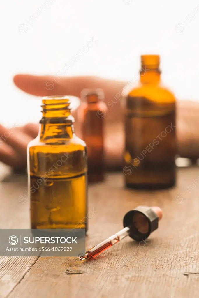 Medical bottles and pipette containing toxic fluid with victim of a crime in the background