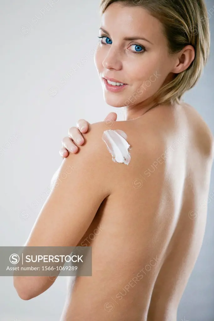 Young woman applying body lotion
